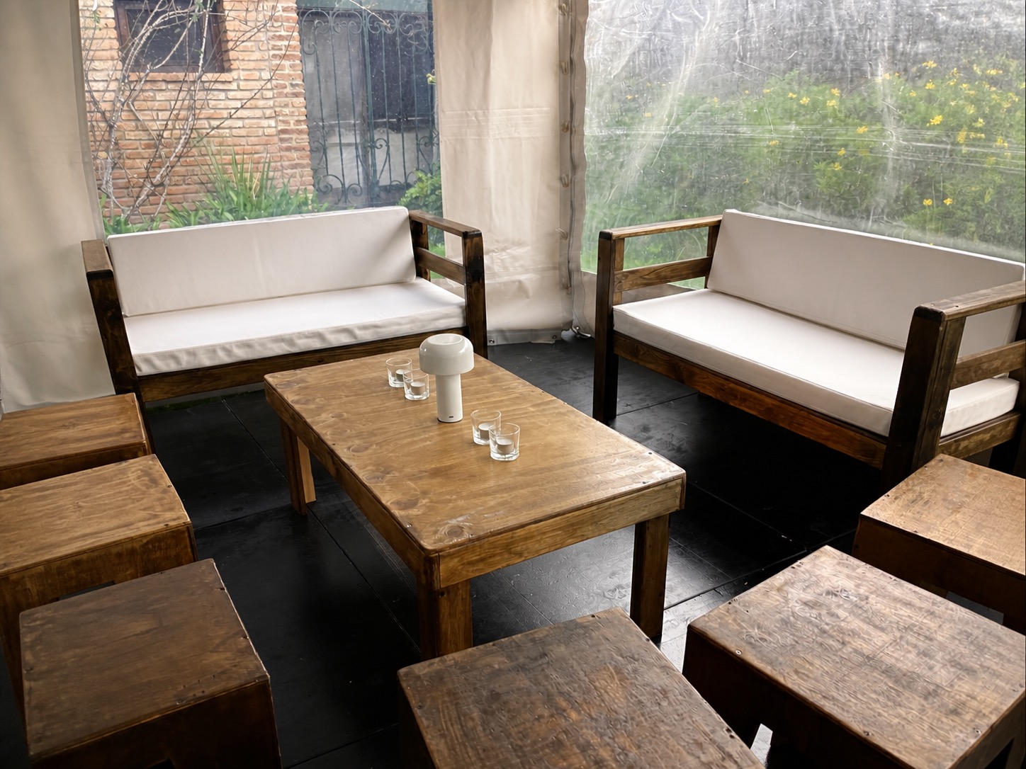 Living de madera con almohadones blancos dentro de carpa real