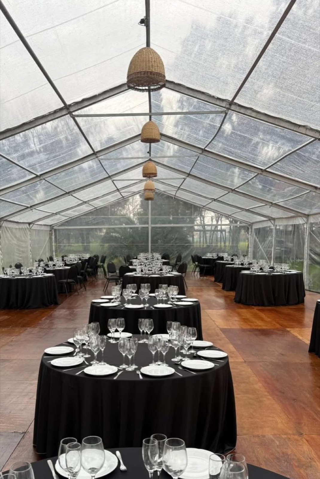 Interior de carpa transparente con piso marron y mesas para evento